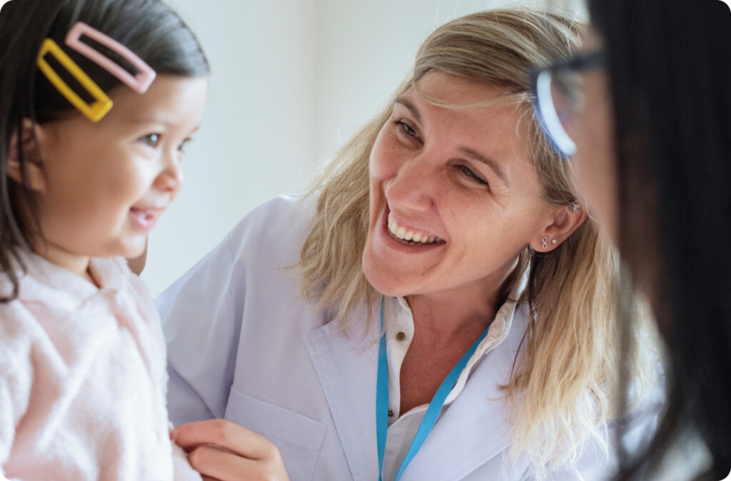 An educator smiling at a young girl, as if she's proud of her, representing good leadership in childcare