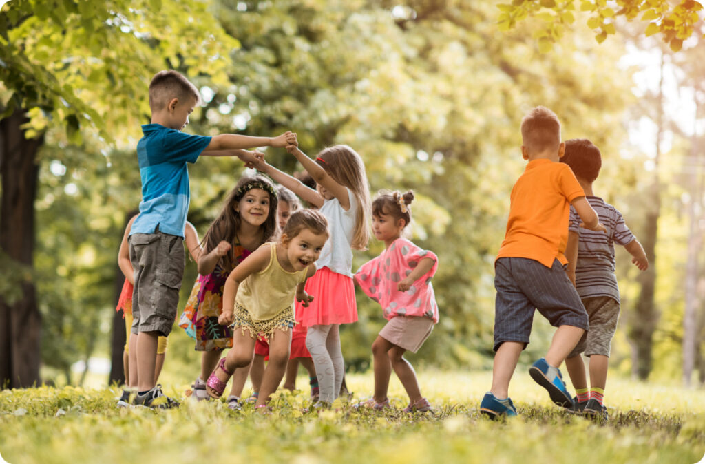 A group of children of varying ages playing London bridge outdoors