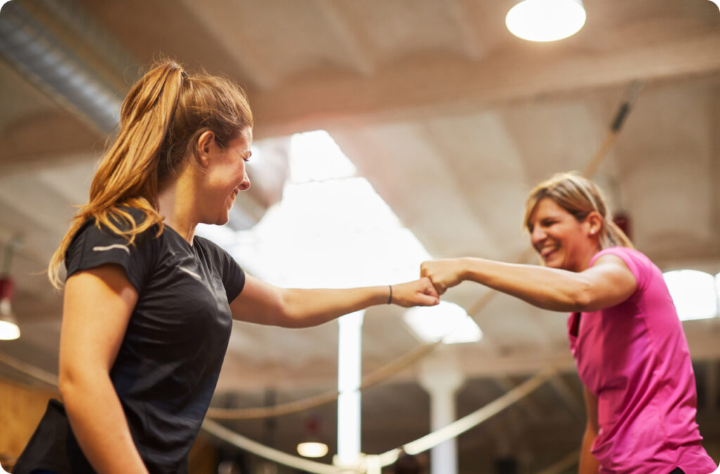 Two women fist bumping, representing teamwork and effective leadership in childcare