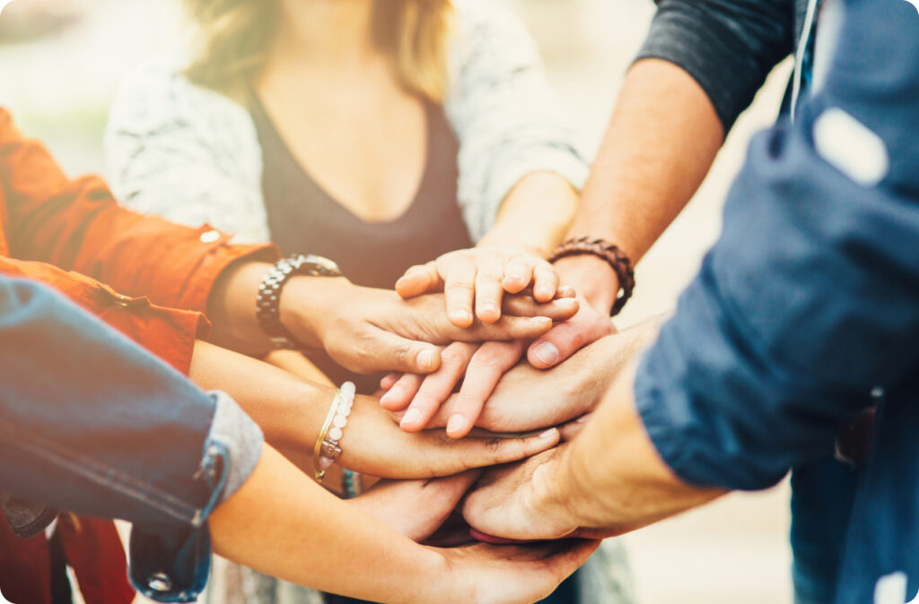 Several hands stacked on top of each other in a "all in" gesture representing teamwork and leadership